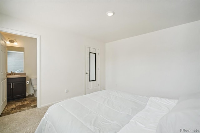 carpeted bedroom featuring sink and ensuite bath