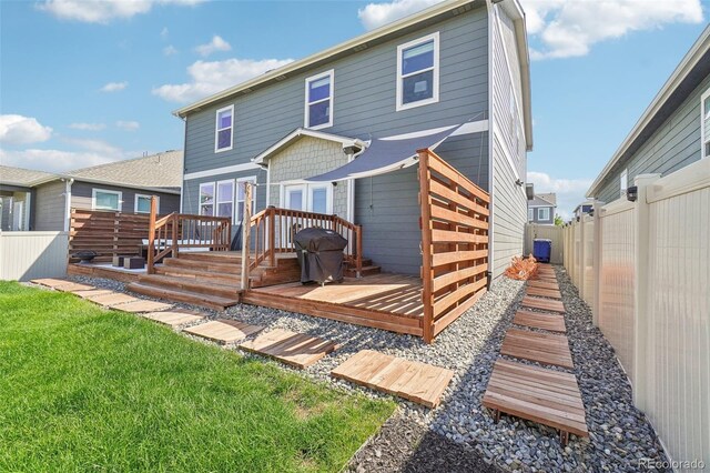 back of property with a wooden deck and a lawn