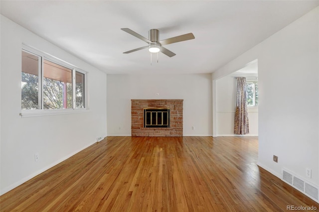 unfurnished living room with hardwood / wood-style flooring, a wealth of natural light, and a brick fireplace