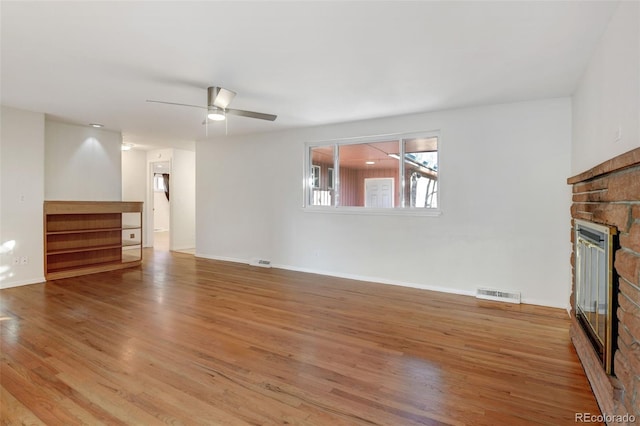 unfurnished living room with a fireplace, ceiling fan, and light hardwood / wood-style flooring