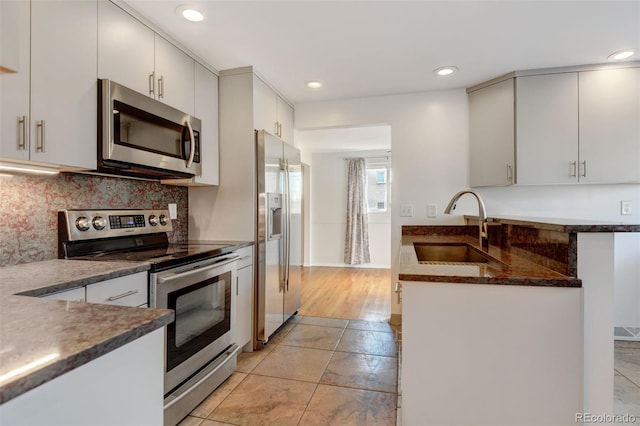 kitchen with sink, white cabinets, light tile patterned flooring, and appliances with stainless steel finishes