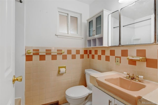 bathroom with vanity, toilet, and tile walls