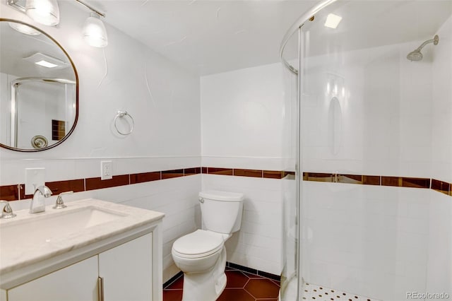 bathroom featuring vanity, a shower with door, tile patterned flooring, toilet, and tile walls