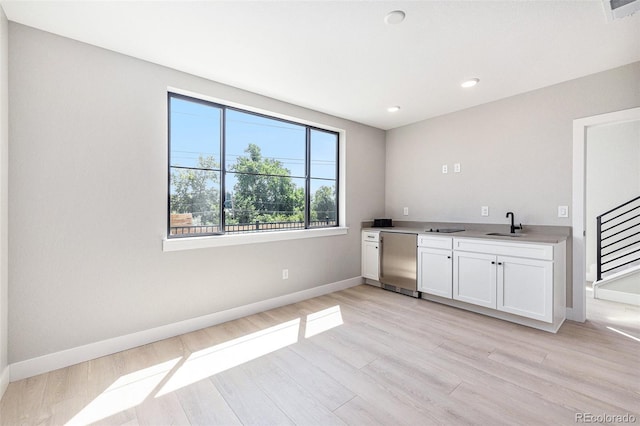 kitchen featuring white cabinets, light wood-style floors, and baseboards