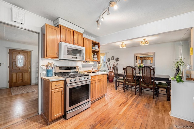 kitchen featuring stainless steel gas stove, light wood finished floors, open shelves, light countertops, and white microwave