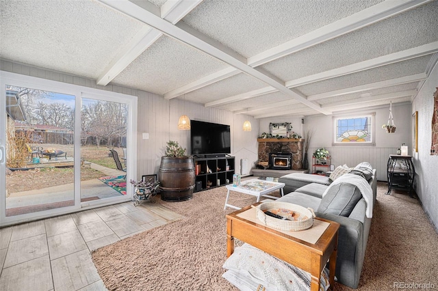 living room with beamed ceiling, a textured ceiling, a stone fireplace, and coffered ceiling