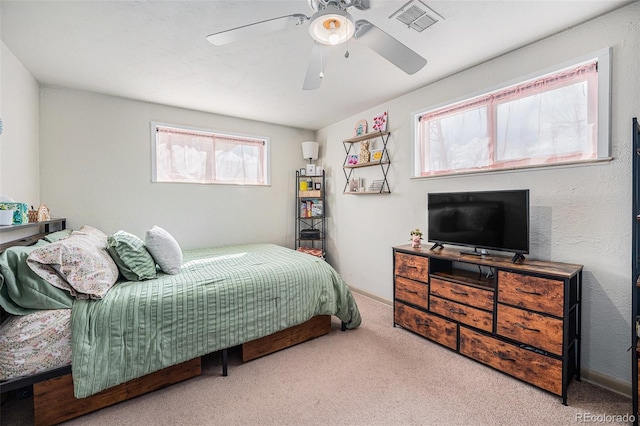 carpeted bedroom with a ceiling fan and visible vents