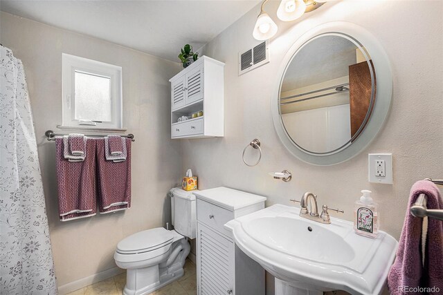 bathroom with tile patterned floors, toilet, visible vents, and a sink