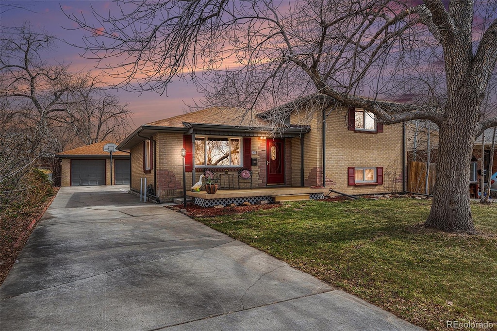 7930 Quitman St, Westminster, CO 80030 - split level home with a porch, brick siding, a yard, driveway, and a detached garage