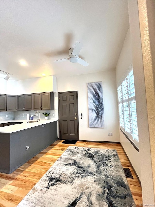 kitchen with backsplash, light hardwood / wood-style floors, sink, and ceiling fan