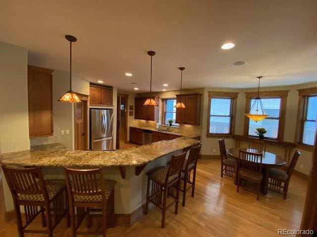 1145 S Williams St, Denver, CO 80210 - kitchen featuring stainless steel fridge, a peninsula, light wood-type flooring, light stone counters, and a breakfast bar area
