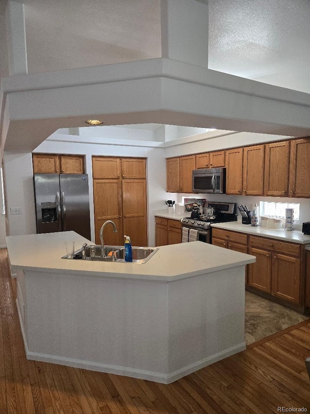 kitchen with dark hardwood / wood-style flooring, sink, an island with sink, and appliances with stainless steel finishes