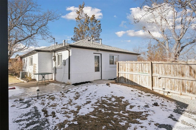 snow covered rear of property featuring a patio and cooling unit