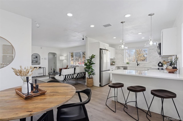 kitchen featuring sink, white cabinetry, light wood-type flooring, backsplash, and appliances with stainless steel finishes