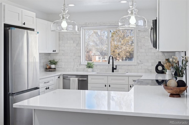 kitchen featuring decorative light fixtures, stainless steel appliances, decorative backsplash, white cabinets, and sink