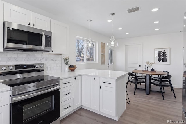 kitchen with decorative light fixtures, stainless steel appliances, and white cabinetry