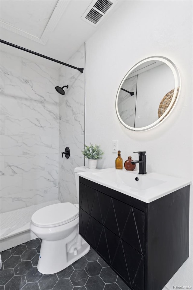 bathroom with toilet, tiled shower, and vanity