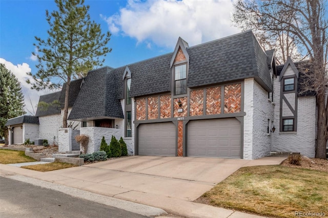 view of front of house featuring brick siding, a shingled roof, concrete driveway, mansard roof, and a garage