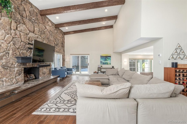 living room with beamed ceiling, a fireplace, a towering ceiling, and wood-type flooring