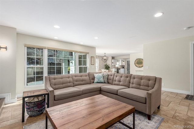 living area with stone tile floors, a notable chandelier, recessed lighting, and baseboards