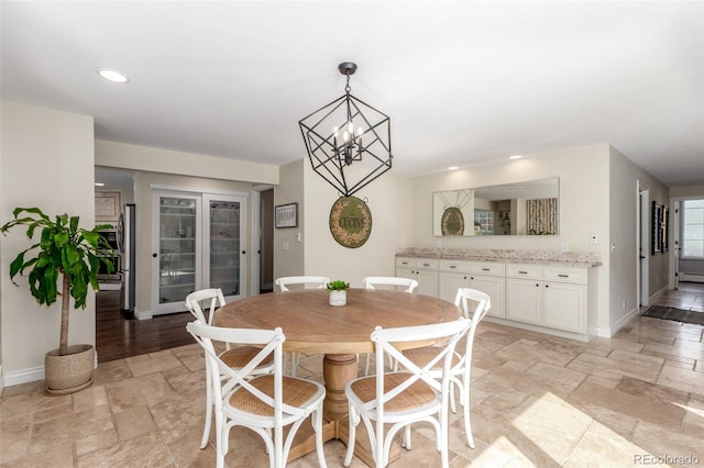 dining area featuring stone tile floors, recessed lighting, baseboards, and a chandelier