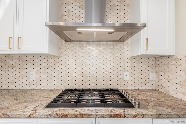 kitchen with tasteful backsplash, stainless steel gas stovetop, wall chimney exhaust hood, and white cabinetry