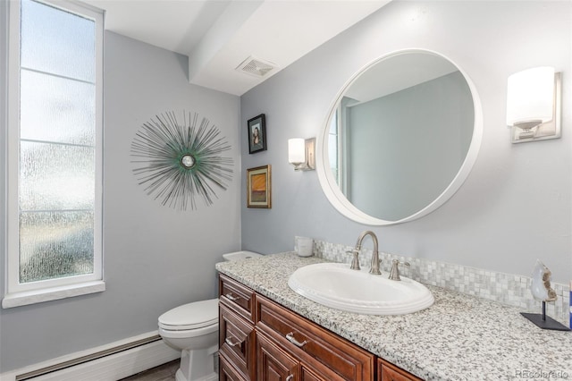 bathroom with a baseboard heating unit, toilet, vanity, and visible vents