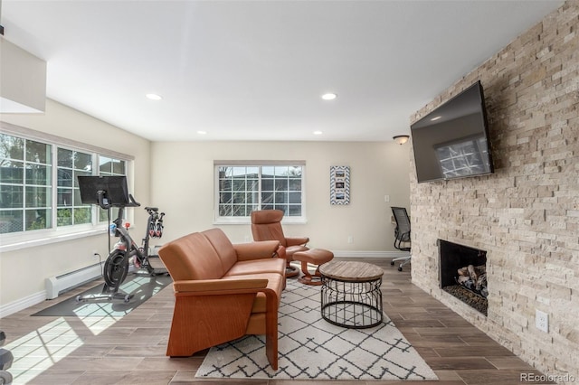 living area with a wealth of natural light, a baseboard heating unit, wood tiled floor, and a fireplace