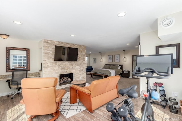 living area with a stone fireplace, light wood-style flooring, and recessed lighting