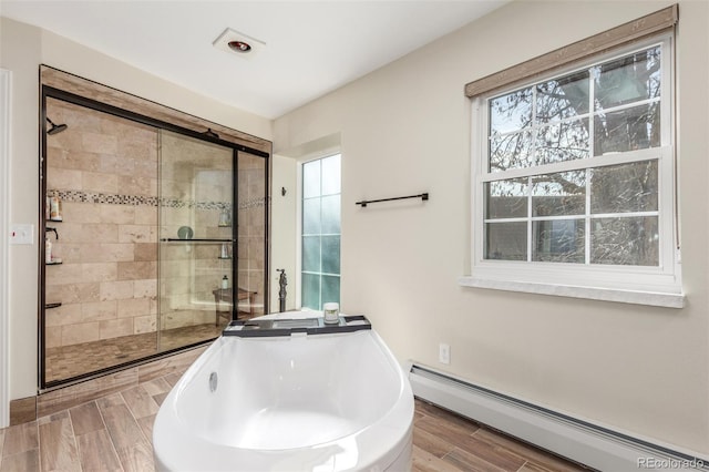 full bathroom with a freestanding tub, a baseboard heating unit, wood finish floors, and a stall shower