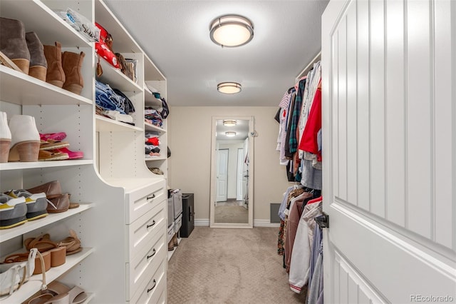 walk in closet featuring light colored carpet