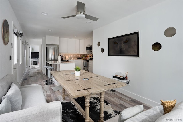 dining room with sink, light hardwood / wood-style flooring, and ceiling fan