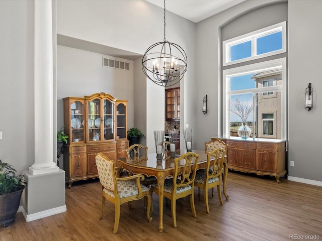 10531 Lieter Pl, Lone Tree, CO 80124 - dining area with decorative columns, a chandelier, wood finished floors, a high ceiling, and baseboards