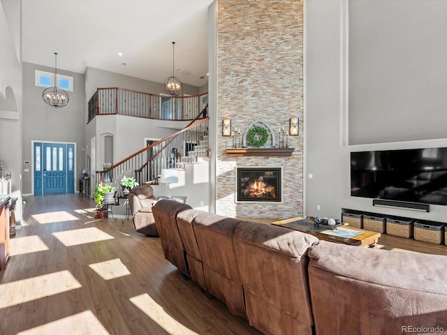 10531 Lieter Pl, Lone Tree, CO 80124 - living area with a chandelier, a towering ceiling, stairway, wood finished floors, and a stone fireplace