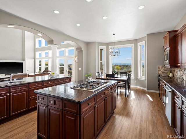 10531 Lieter Pl, Lone Tree, CO 80124 - kitchen with appliances with stainless steel finishes, arched walkways, recessed lighting, light wood-style floors, and a center island