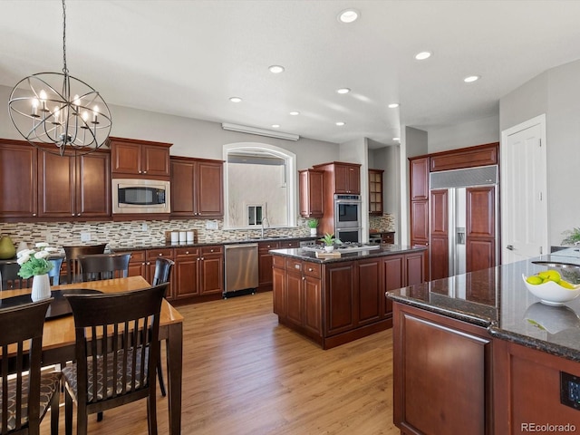 10531 Lieter Pl, Lone Tree, CO 80124 - kitchen featuring built in appliances, tasteful backsplash, a chandelier, light wood-style flooring, and a center island