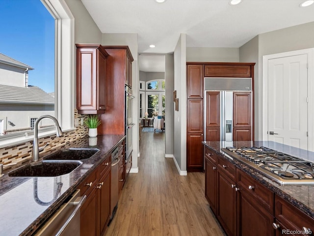 10531 Lieter Pl, Lone Tree, CO 80124 - kitchen with stainless steel appliances, a sink, light wood finished floors, baseboards, and dark stone countertops