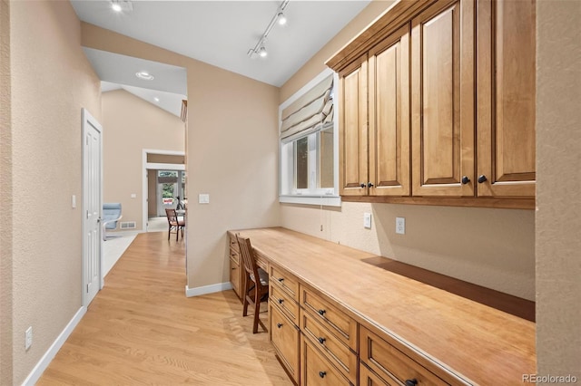 4398 Carter Trl, Boulder, CO 80301 - kitchen featuring built in study area, light wood-type flooring, lofted ceiling, brown cabinets, and light countertops