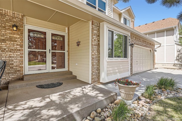 entrance to property with brick siding, driveway, and a garage