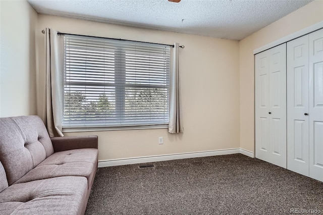 sitting room featuring carpet floors, baseboards, and a textured ceiling