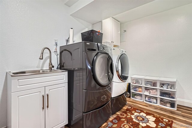 washroom with independent washer and dryer, cabinet space, wood finished floors, and a textured wall