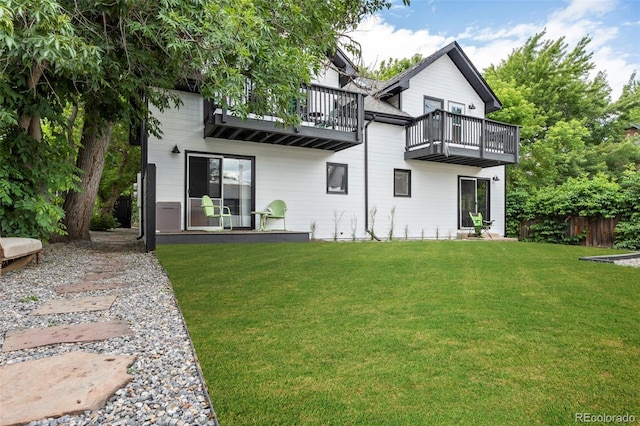 back of house featuring a yard, a balcony, and fence