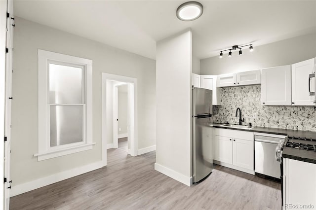 kitchen featuring a sink, white cabinetry, appliances with stainless steel finishes, decorative backsplash, and dark countertops