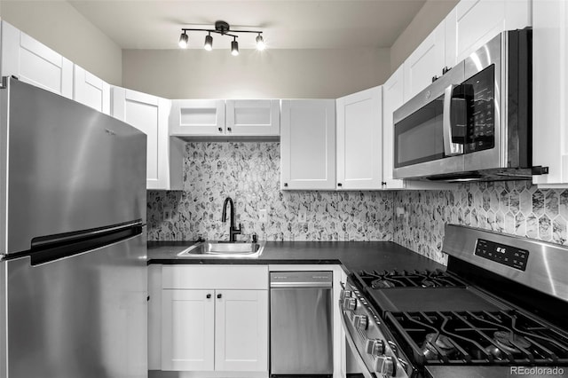 kitchen with a sink, white cabinetry, appliances with stainless steel finishes, tasteful backsplash, and dark countertops