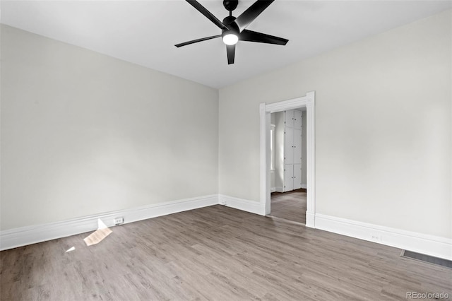 empty room featuring baseboards, visible vents, ceiling fan, and wood finished floors