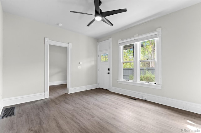 empty room featuring a ceiling fan, baseboards, visible vents, and wood finished floors