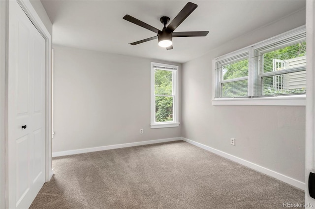 spare room featuring ceiling fan, carpet, and baseboards