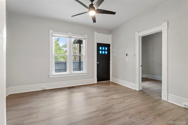 foyer with a ceiling fan, visible vents, baseboards, and wood finished floors