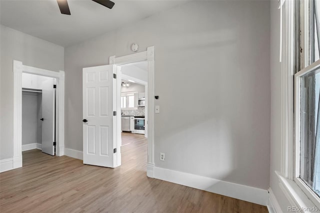 unfurnished bedroom with light wood-type flooring, a ceiling fan, and baseboards