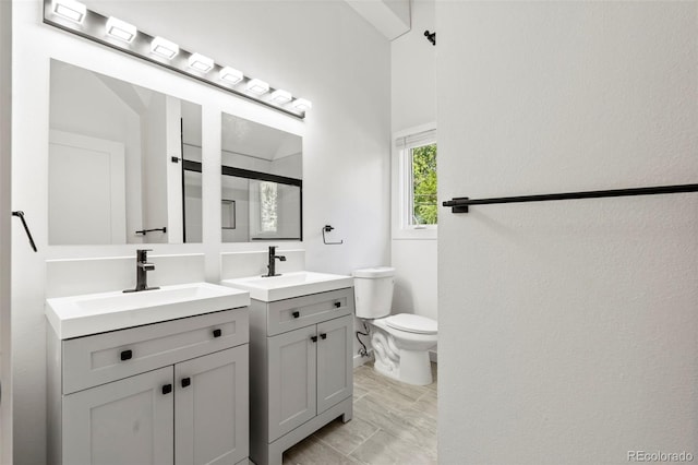 bathroom with toilet, two vanities, and a sink